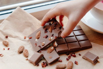 A bar of milk chocolate. Homemade milk chocolate with almonds and dried strawberries. Pieces of milk chocolate. Unlabeled milk chocolate bar