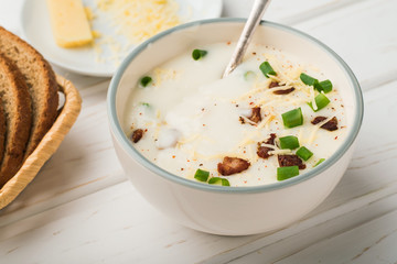 A bowl of potato soup with milk and bacon on wooden background