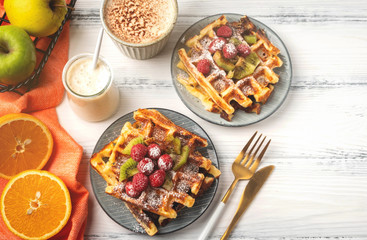 Belgian waffles, coffee, yogurt, fruits on a white wooden background, breakfast concept.