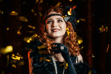 Portrait of vintage styled woman dressed in Great Gatsby era dancing under confetti rain on velours background. Roaring twenties, retro, party, fashion concept