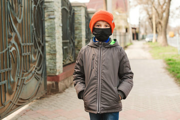 Boy wears face mask for protection outdoors. Kid in safety mask walking at street.