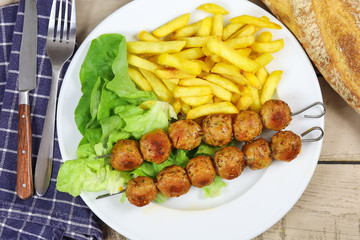 brochettes de poulet et frites dans une assiette
