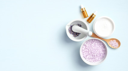 Homemade lavender cosmetic on blue background with copy space. Natural organic beauty products for body care and skin treatment. Flat lay, top view. Beauty salon banner mockup