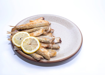 Fried smelt, fish lies on a clay plate, lemon wedges. Fresh catch, copy space
