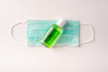 Protective medicine face mask, antiseptic gel on light background. Top view. Copy space