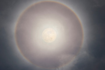 Super moon with a circular rainbow halo around the moon formed by the mist