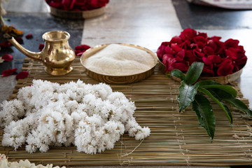 items for the Indian Yajna ritual. garland of white flowers, red rose petals and copper dish with...