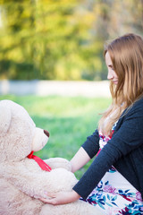 Pregnant young woman outside with teddy bear