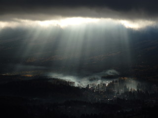 Dolina we mgle oświetlona aurą zza chmur