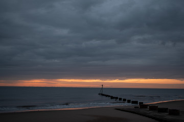 Fototapeta na wymiar sunrise at the coast in mablethorpe uk. moody skies and blue sea