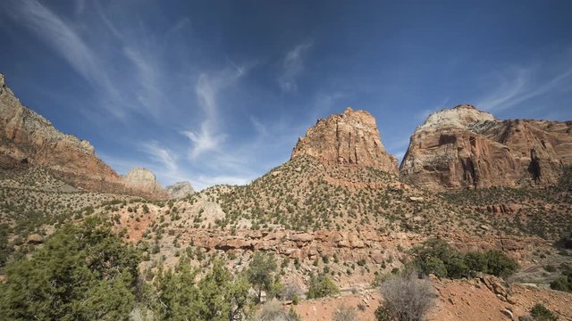A timelapse of clouds flowing over orange cliffs and white rock faces in Zion National Park, located along the East Highway leading out of the park.