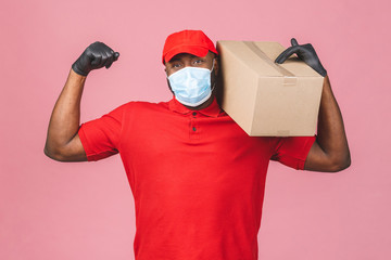 Fototapeta na wymiar Delivery african american man employee in red cap blank t-shirt uniform face mask gloves hold empty cardboard box isolated on pink background. Service quarantine pandemic coronavirus virus 2019-ncov.