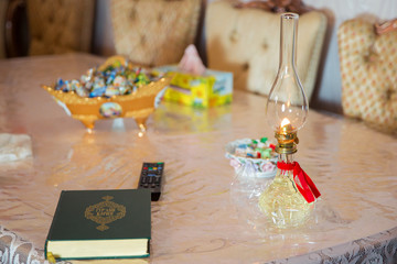 vintage kerosene oil lantern lamp burning with a soft glow light in an antique rustic country barn . There is a book of the Quran on the table. Book of Koran. Lantern kerosene oil Lamp for a wedding .