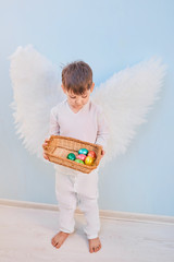 Angel boy in white with wing.Easter eggs