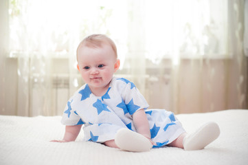 Fototapeta premium little girl 6 months old with big blue eyes in the house is happy