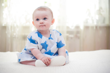 little girl 6 months old with big blue eyes in the house is happy