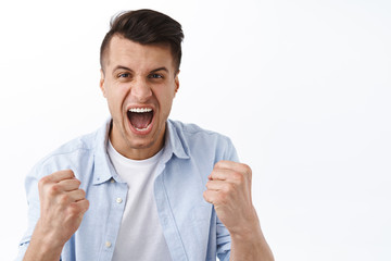 Come o fight. Portrait of excited handsome man, shouting as rooting for team, watching sport game, clench fists and screaming, celebrating victory, triumphing over score, winning prize