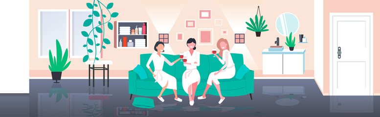 beautiful women in bathrobes drinking wine having fun home care concept girls sitting on sofa relaxing during bachelorette party modern living room interior full length horizontal vector illustration