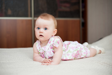 little girl 6 months old with big blue eyes in the house is happy