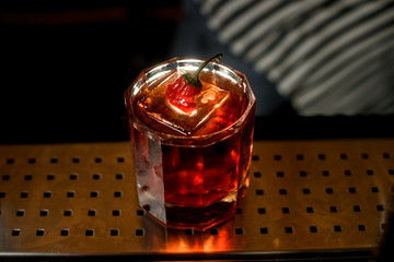 close-up glass with drink and piece of ice standing at the bar