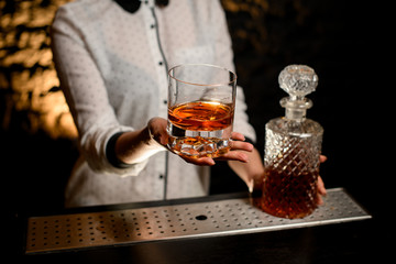 Close-up view of glass with cocktail that girl holds in her hand at bar