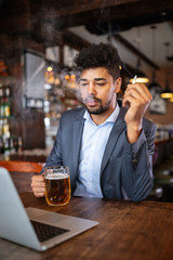 People and bad habits concept. Man drinking beer and smoking cigarette at pub
