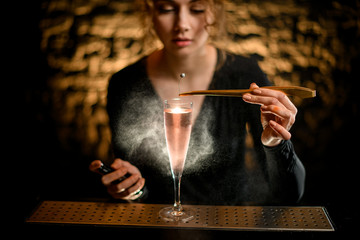 close-up girl at bar decorates by flower glass with light rose cocktail and sprinkles on it