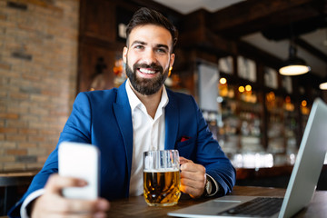 Handsome young business man, blogger or remote working with laptop in bar