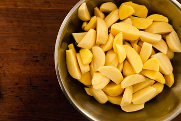 seasoned raw chopped potatoes,bowl of raw potatoes standing on the table,peeling potatoes for cooking,cooking baked potatoes,hand sprinkles seasoning in potatoes