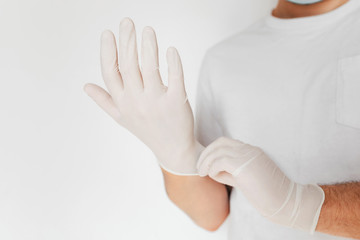 A man putting on medical protective gloves, on light background. Avoid contaminating Corona virus Covid-19 concept