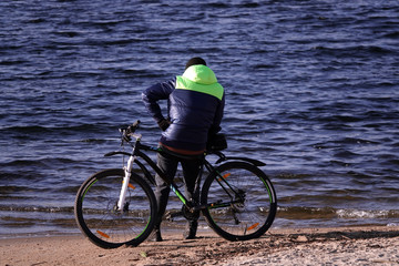 A man with a bicycle looks at the water