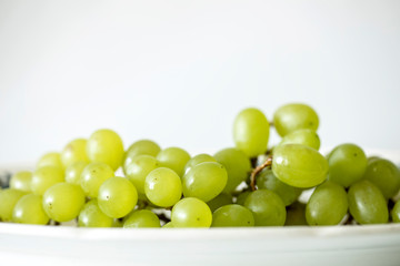 Green grapes in the plate on the white background