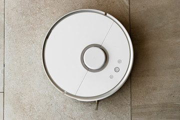 Robot vacuum cleaner during cleaning,white robot vacuum cleaner cleans the floor from debris,home cleaning with an electric vacuum cleaner,vacuum cleaner electric robot cleaning technology