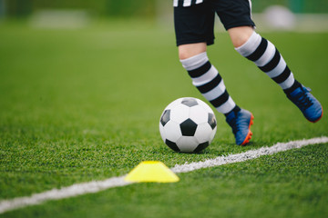 Detail soccer player kicking ball on pitch sideline. Soccer player on a game. Detail soccer background. Close up of legs and feet of footballer on green grass pitch