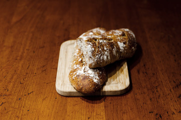 home baked fresh bread lying on a wooden table,two breads lie on a cutting board,branded home-baked bread,baguette with seeds,bran loaf