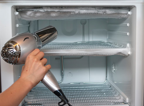 an ice chest freezer is defrosted with a hair dryer