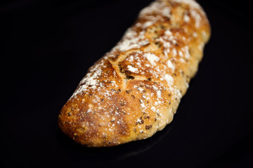 baked homemade bread on a black background,homemade fresh bread with seeds and flour,fresh baguette on a dark background,bread with homemade dough