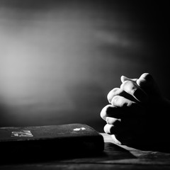 Hands and the Bible on old wooden table, coronavirus pandemic, pray to God in the dark, copy space
