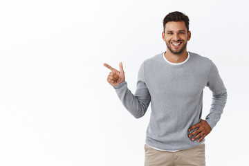 Good-looking smiling, happy bearded 25s man in grey sweater, talking about product features, suggest place to grab cup coffee sit and talk to friend he met street, standing joyful, recommend promo