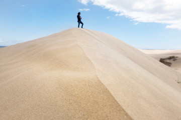 Fototapeta na wymiar Panoramic view of huge dune in Maspalomas desert. New experiences traveling around the world. Unrecognizable man enjoying freedom. Travel and holidays concept. Canary Islands natural landscape.