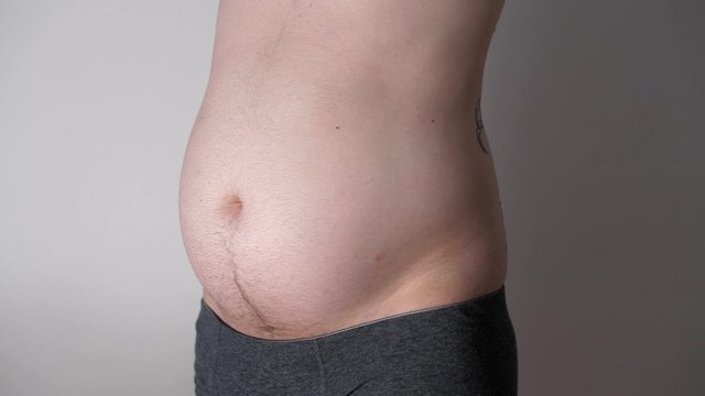 Fat male  stomach. Weight loss or weight gain during quarantine. Attractive man with obese bare belly. Close-up of male beer belly of sexy man. Bodypositive
