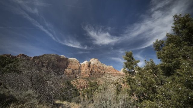 A timelapse of clouds flowing over orange cliffs and rock faces in Zion National Park, located along the East Highway leading out of the park.