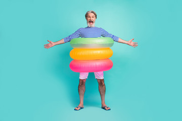 Full length photo of funny aged seaman swimmer stand inside three colorful circle lifebuoy wear...