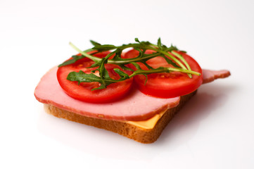 Fototapeta na wymiar A sandwich of balyk, cheese, bread, tomatoes and arugula on a white plate view from the side and from the top