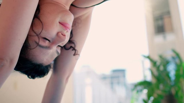 Young woman with black hair in leggins doing yoga excersices looking down dog at home in loft studio available sun light shot in 4k