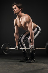 Fototapeta na wymiar Side view of shirtless muscular man lifting weights