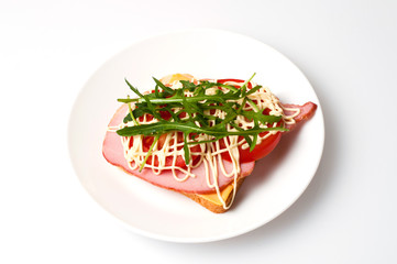 Sandwich of bread for toast, sturgeon, tomatoes, arugula, cheese and mayonnaise on a white plate in the view from the top flat lay