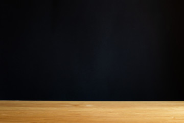 Empty wooden tabletop isolated on dark background. For your product placement or montage with focus to the table top in the foreground. Empty wooden shelf