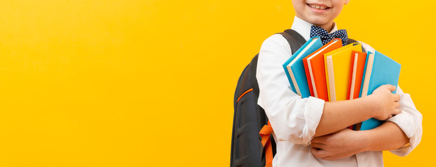 Close-up boy carrying stack of books