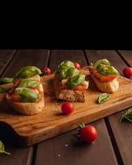 toast bread with mozzarella basil and cherry tomatoes on wooden background